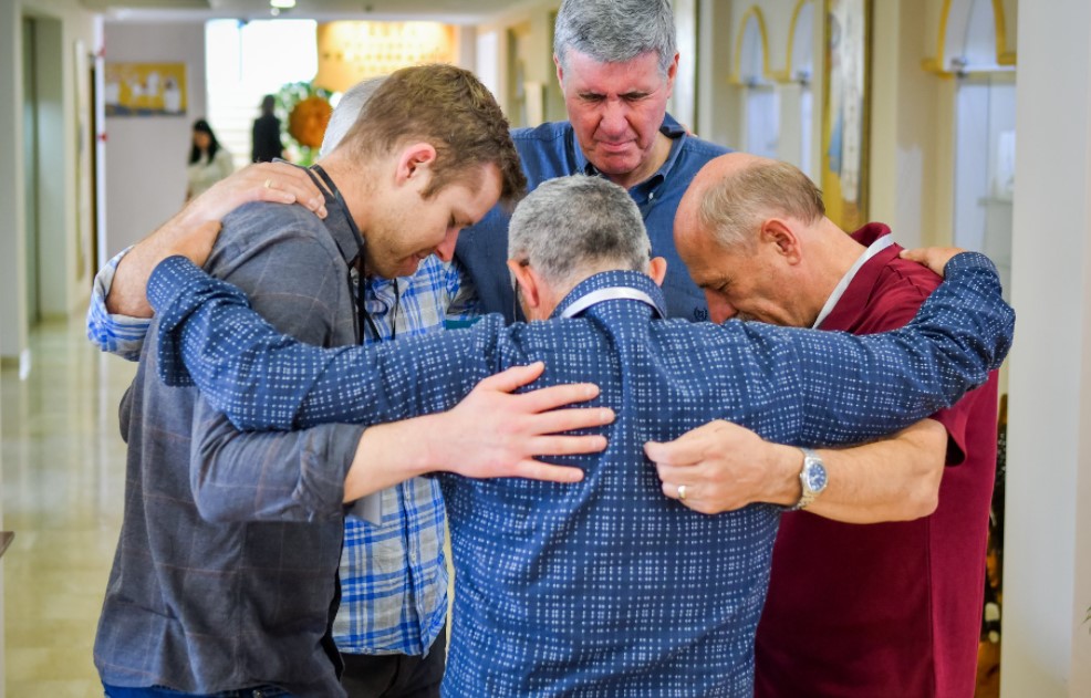 Colin Smith (centro, costas) ora com um grupo de crentes na Albânia