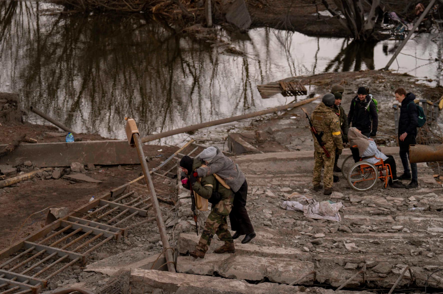 Soldados ajudam moradores a atravessar ponte destruída