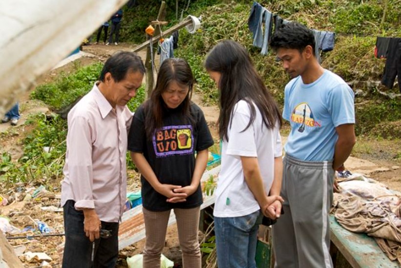 Missionário ora com pessoas