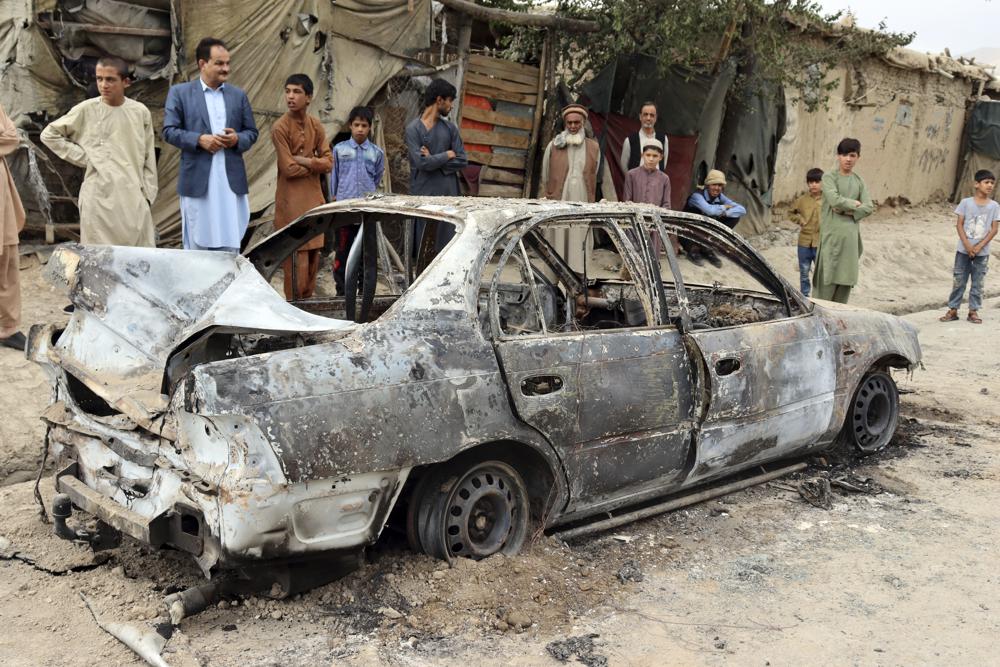 Moradores diante de veículo destruído por foguete em Cabul